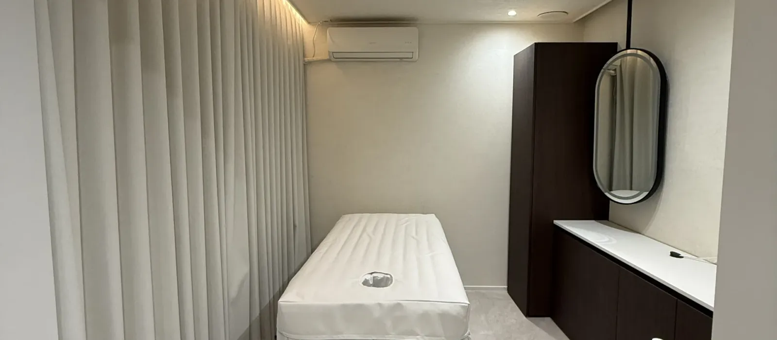 カーテンと鏡、施術ベッドが置かれたエステールの個室