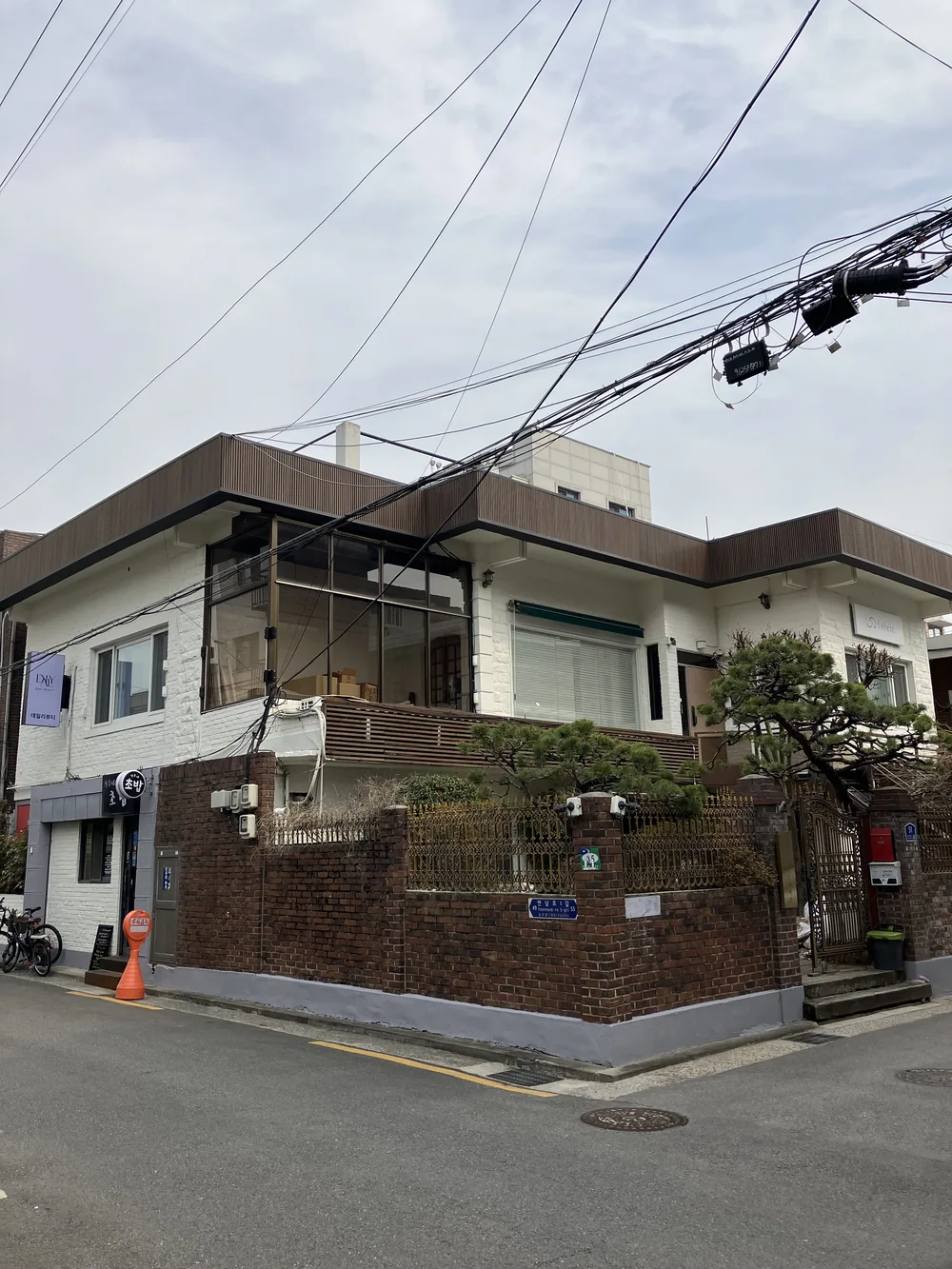 延南洞の角地に建つ白い2階建ての一軒家とれんがの塀 — 全身のトーンアップケアを受けるエステールエステの外観